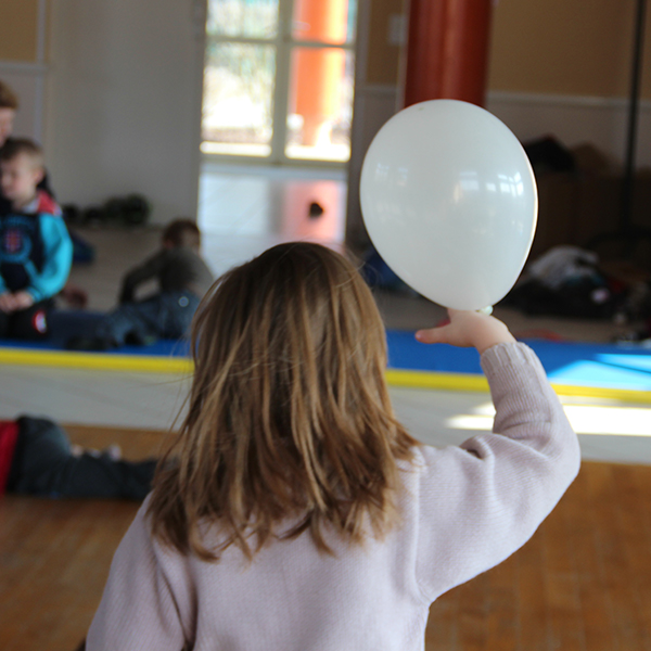 Photographie d'un enfant qui tient un ballon  de baudruche blanc lors d'un atelier de pratique artistique.