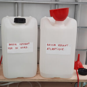 Deux bidons d'eau présents à côté de la cabine de collecte de paroles.