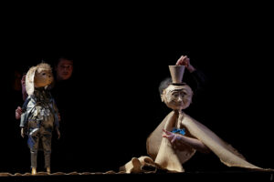 Peddy Bottom est sur scène avec une marionnette qui porte un chapeau.