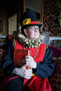 Le comédien porte un costume royal et pose avec sérieux.