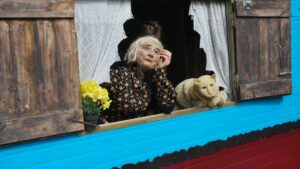 La marionnette est appuyée sur la fenêtre, songeuse. Son chat est à côté d'elle.