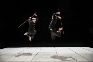 Les danseurs sautent en l'air avec deux bâtons.