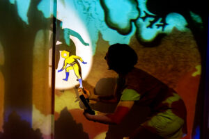 La comédienne manipule une marionnette pour faire du théâtre d'ombre.