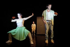 Deux danseurs regardent leur portable, le troisième danseur est en arrière.