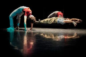 Deux danseurs font le pont, le troisième est étendu en suspension dans les airs.
