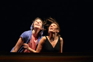 Les deux comédiennes regardent en l'air en souriant.