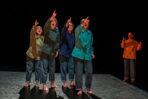 Quatre danseuses pointes du doigt vers le public, la cinquième danseuse est en arrière-plan.