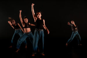 Trois danseuses lèvent le poing vers le ciel, une autre danseuse tend la main vers elles.