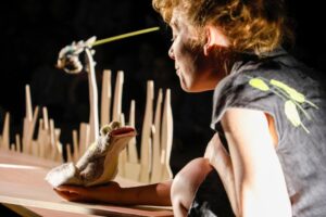 La comédienne tient une marionnette de grenouille.