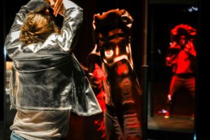 Le danseur est face à deux silhouettes rouges.