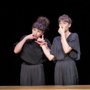 Une comédienne se bouche le nez, l'autre fait semblant d'être au téléphone.