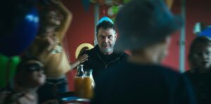 Le comédien est assis avec des enfants à une table d'anniversaire.