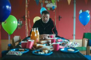 Le comédien est assis seul à une table d'anniversaire.