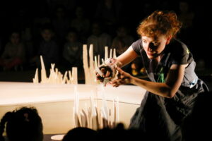 La comédienne monter une marionnette au public.