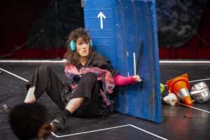 La comédienne se cache derrière une planche en bois bleue.