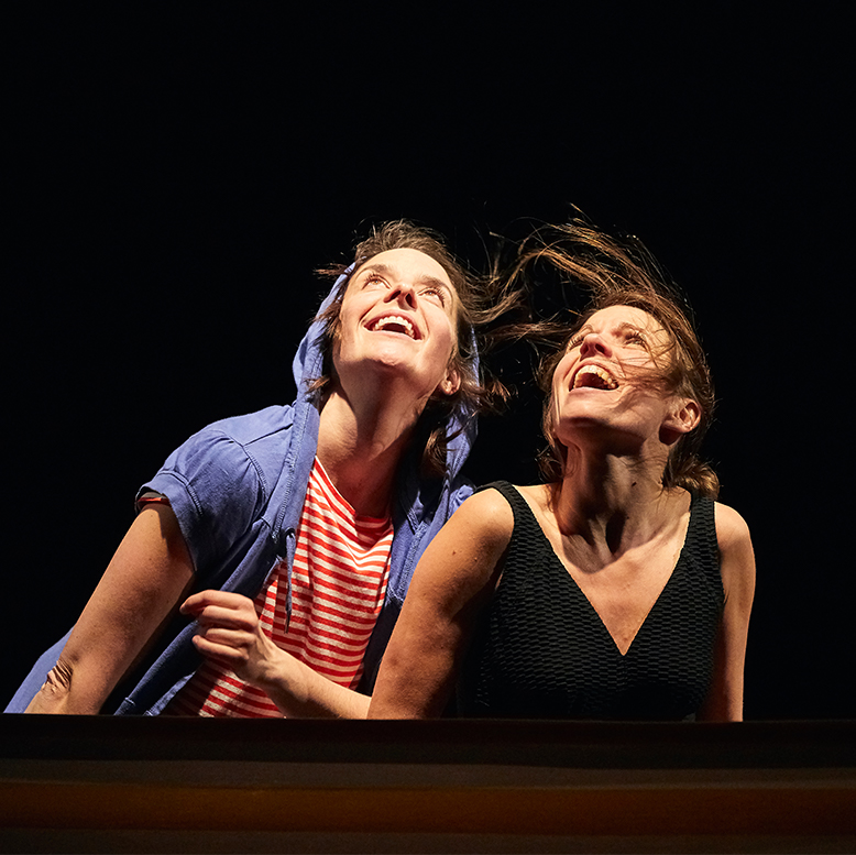 Les deux comédiennes regardent le ciel en souriant.