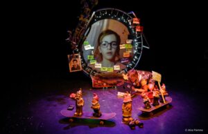 La comédienne circule entre un miroir-écran vidéo et des nains de jardin.