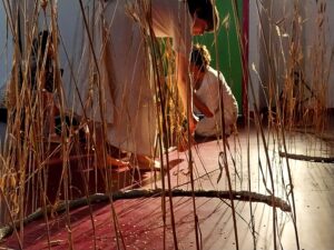 La comédienne balaye des grains de blé au sol.