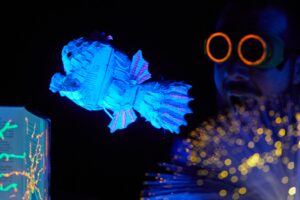 Un poisson marionnette passe devant le comédien.