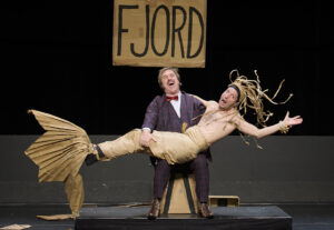 Le comédien porte l'autre comédien déguisé en sirène.