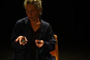 La comédienne tient des bouts de tissus et des boutons dans ses mains.