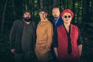 Les quatre musiciens posent devant un fonds représentant une forêt.