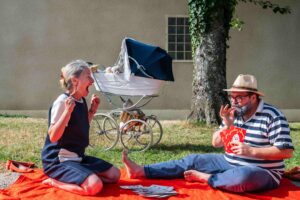 Les deux grands-parents jouent aux cartes sur une nappe de pique-nique.