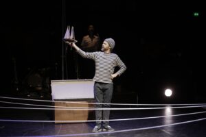 Le comédien tient en l'air une maquette de bateau.