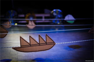 Dessins de bateaux sur des cartons qui avancent sur des fils tendus.