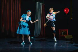 La comédienne montre le danseur qui est en train de sauter.
