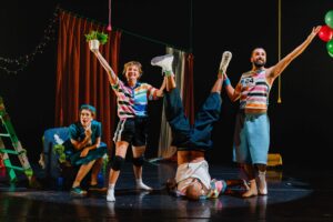 Deux danseurs tiennent en l'air les jambes du troisième danseur.