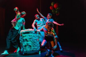 Les danseurs et la comédienne sont rassemblée autour d'un objet à fourrure.