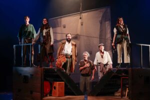 Six pirates sont sur un bateau, face au public.