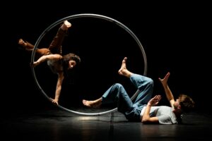 Les deux circassiens font des figures au sol et avec une roue cyr.