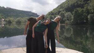 Les trois danseurs se penchent sur le côté, devant un lac.