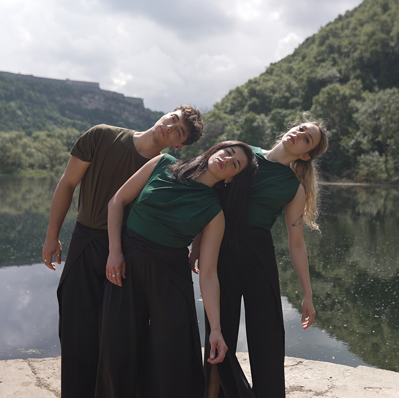 Les trois danseurs se penchent sur la droite devant un lac.